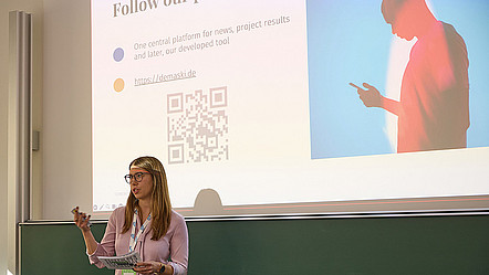 Maja Denisova steht vor einer Präsentationsfolie.
