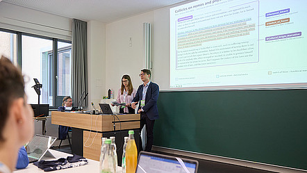 Dr. Tobias Hirsch steht am Rednerpult vor einer Präsentationsfolie