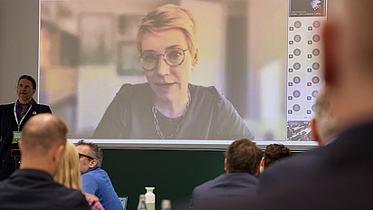 Auf dem Bild ist im Hintergrund Carolin Lindekamp bei ihrem Online Vortrag zu sehen